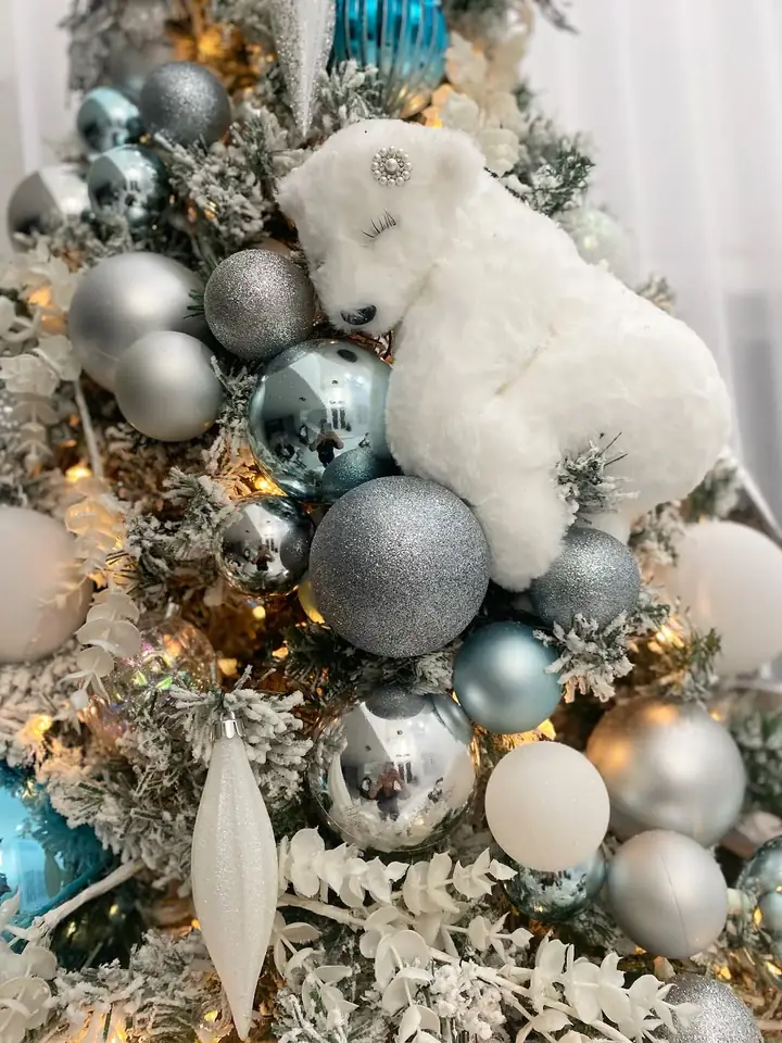 A flocked polar bear resting among silver and icy blue ornaments