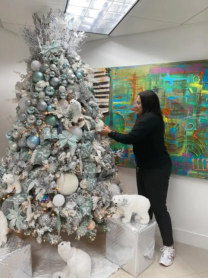 A Rose Art and Decor designer installing a teal and silver Christmas tree in a Miami home